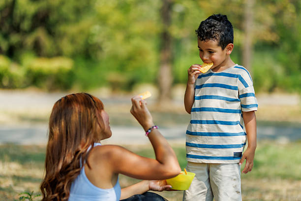 istock Mother and son sharing a snack in a sunny park on a warm afternoon 2235647929