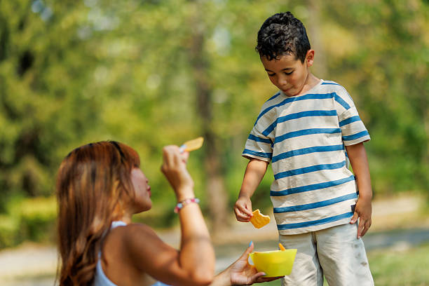 istock Mother and child enjoying a snack outdoors in a sunny park setting 2235647935