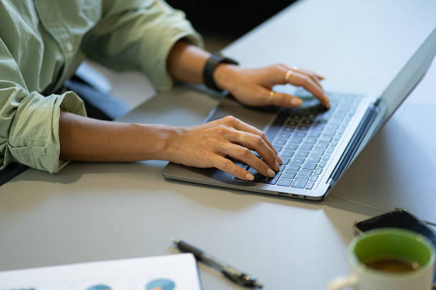 Office worker typing on laptop at desk, working on business project