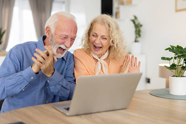 istock Elderly couple claps joyfully at digital screen together 2235648895