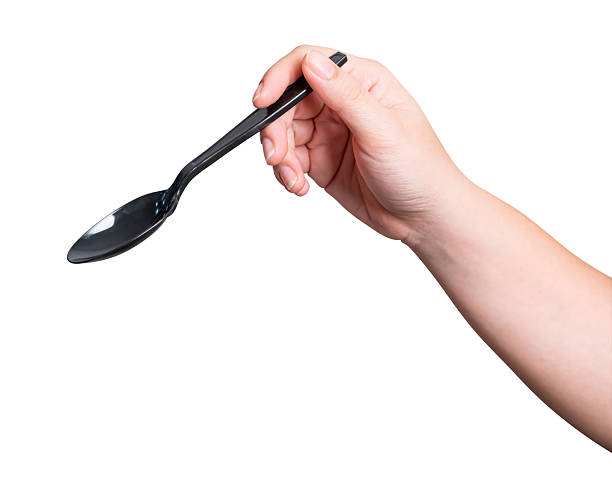 istock Female hand holding a black plastic spoon isolated on white background. 2235651988