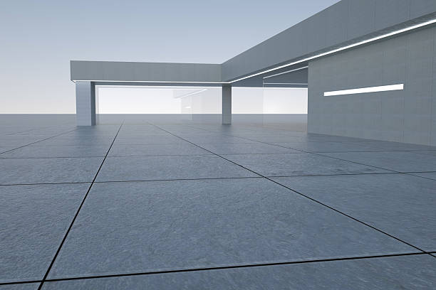 This image shows a modern minimalist building with large glass windows and a tiled floor, featuring a clean and simple design with prominent geometric lines and an emphasis on light and shadow