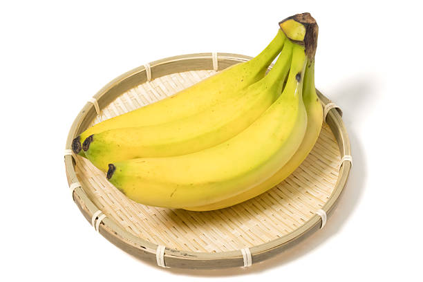 A white plate on a white background with fruit consisting of a yellow and green banana and red apple on the plate