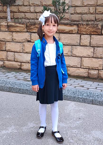 Little girl is outside in school uniform ready to study . High quality photo