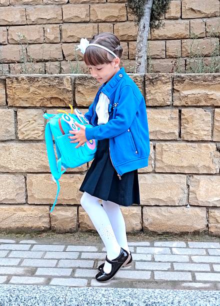 Little girl is outside in school uniform ready to study . High quality photo