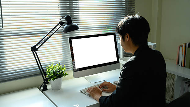 istock Young man working on desktop computer at home office desk with blank screen 2235677772