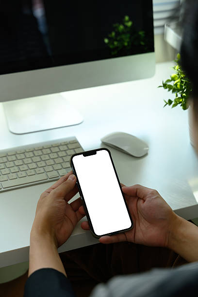 istock Hands holding a smartphone with blank white screen at modern office desk 2235677782