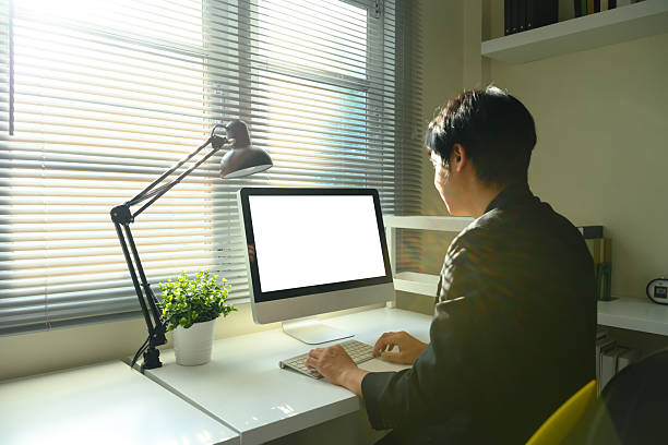 istock Young man working on desktop computer in bright home office with natural sunlight 2235677930