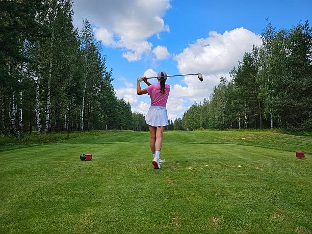 A beautiful women golfer standing on a golf course.