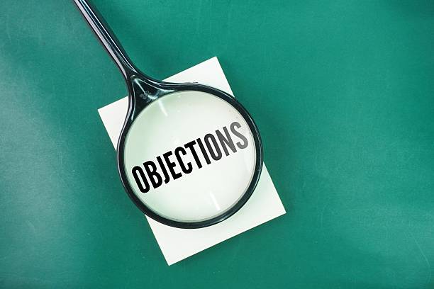 Magnifying glass with the word Objections. a reason or argument offered in disagreement, opposition, refusal, or disapproval
