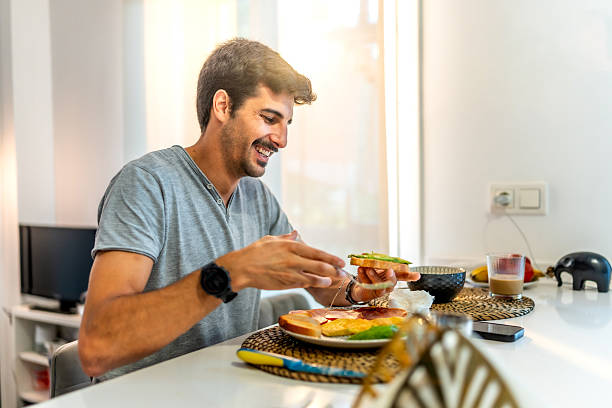 istock Young man enjoying a healthy breakfast at home 2235684480