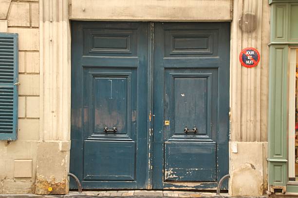 Vintage blue wooden doors in a European urban setting with a worn texture and a 'Jour et Nuit' sign.