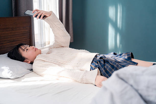 istock Adolescent girl lying in bed using her phone 2235688609