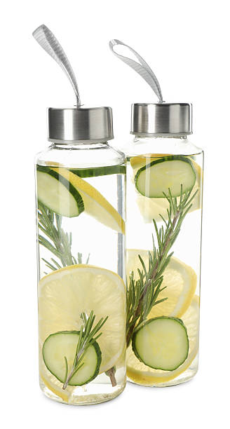 Lemon water with rosemary and slices of cucumber in bottles isolated on white