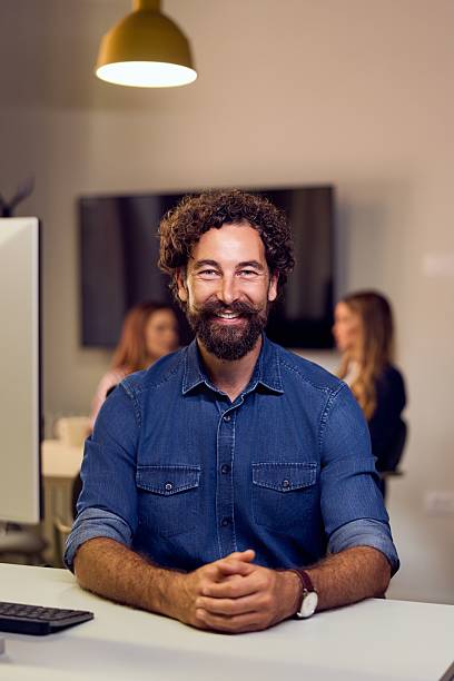 istock Smiling Man Working in a Collaborative Modern Office Space with Colleagues 2235691396
