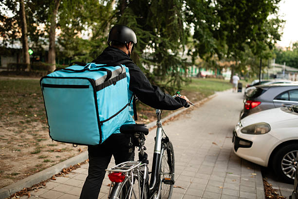 istock Deliveryman walking with bicycle and thermal backpack delivering food order 2235694310