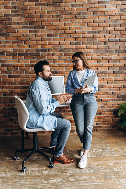 istock Coworkers discussing a project in the office next to a computer 2235694373