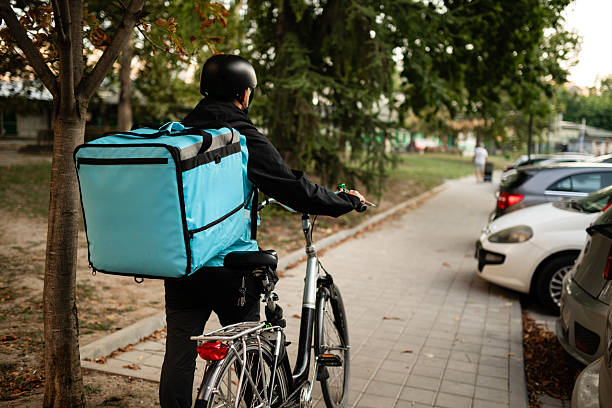 istock Deliveryman pushing bicycle wearing thermal backpack and helmet 2235694437