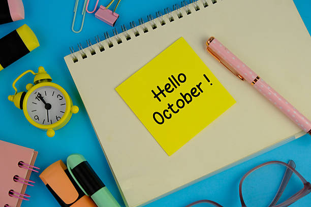 istock text of hello October on table next to computer with  alarm clock. 2235694825