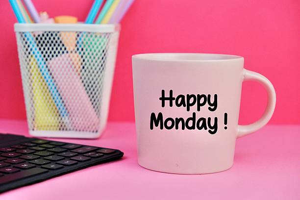 Happy Monday motivational text on yellow morning coffee cup near computer at office workplace. Business background