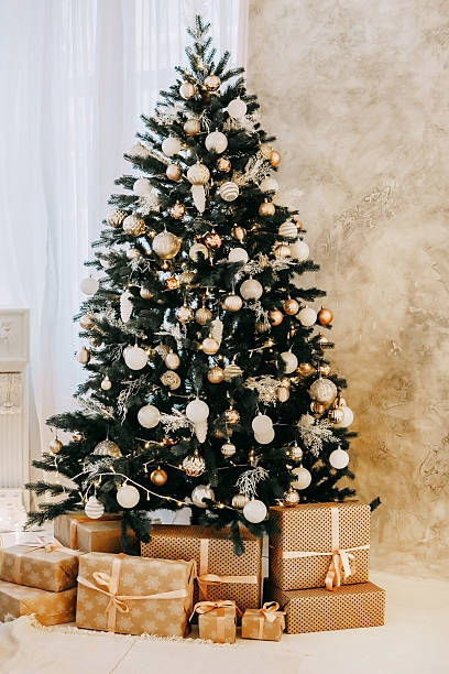 istock Christmas tree decorated with gold and white ornaments, presents underneath for Holiday celebration, festive interior design concept. 2235696383