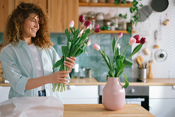 istock Woman putting fresh tulips into the vase 2235696438
