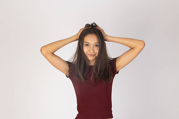 istock Woman is posing with both hands placed on top of her head while looking directly 2235698835