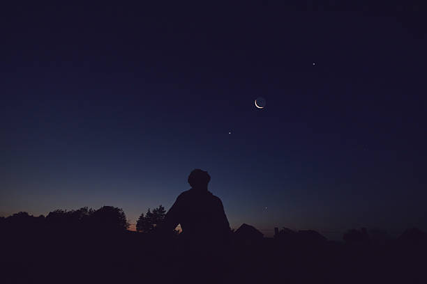 istock Silhouette of a man observing Moon, Milky Way stars, planets and other celestial objects from a dark countryside location. 2235701395
