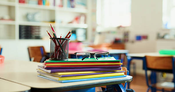 istock Books, colors and spectacles on desk in classroom for learning, education or knowledge with teaching. Glasses, pencils and lesson at elementary school for assessment, test or project at academy. 2235704572