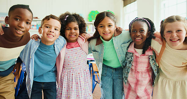istock Education, portrait and students or friends in classroom together for learning, growth or development. Embrace, smile and happy children in back to school class for knowledge, hug and academics 2235704577