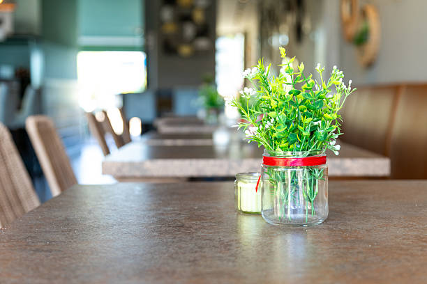 Small green plant in a glass jar decorating a table in a modern style restaurant, creating a cozy and welcoming atmosphere
