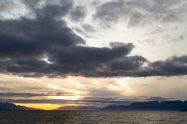 Dramatic sunset over the Beagle Channel in Ushuaia, Tierra del Fuego, Argentina, the southernmost city in the world, with mountains and cloudy sky.Les Eclaireurs Lighthouse (the French name \
