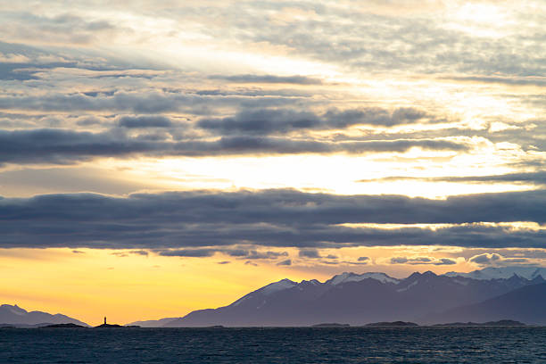 Dramatic sunset over the Beagle Channel in Ushuaia, Tierra del Fuego, Argentina, the southernmost city in the world, with mountains and cloudy sky.Les Eclaireurs Lighthouse (the French name \
