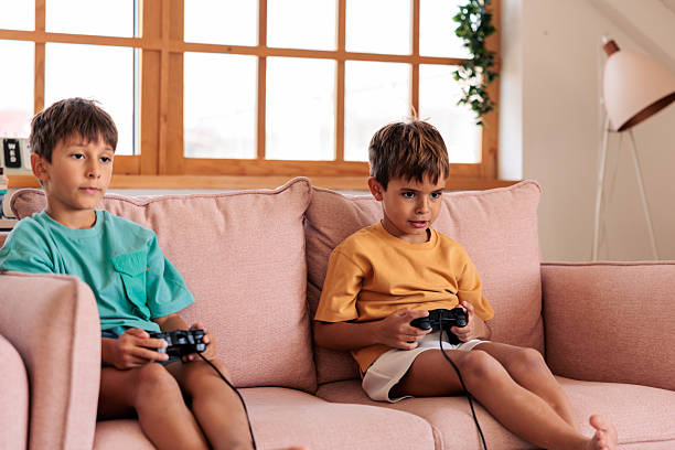 istock Two Boys Playing Video Games on Sofa 2235707244