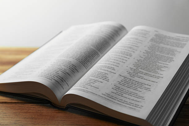 Open Holy Bible in English language on wooden table, closeup