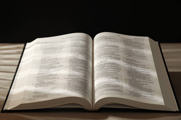 istock Open Holy Bible in English language on beige table, closeup 2235713782