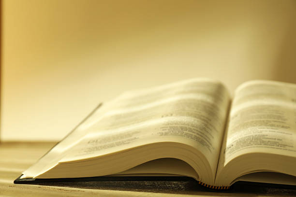 istock Open Holy Bible in English language on beige table, closeup 2235713788