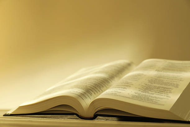 istock Open Holy Bible in English language on beige table, closeup 2235713816