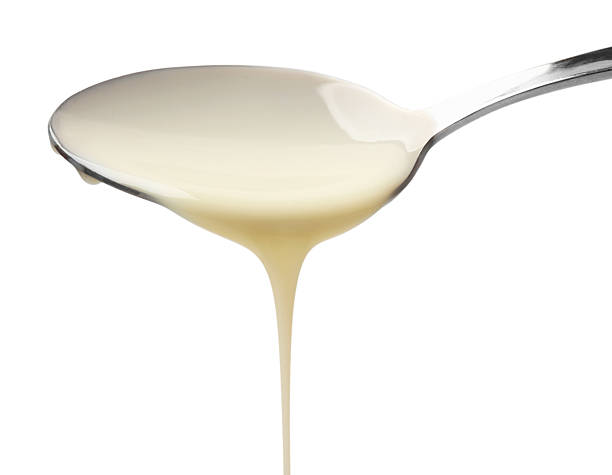 istock Delicious condensed milk pouring from spoon isolated on white 2235717920