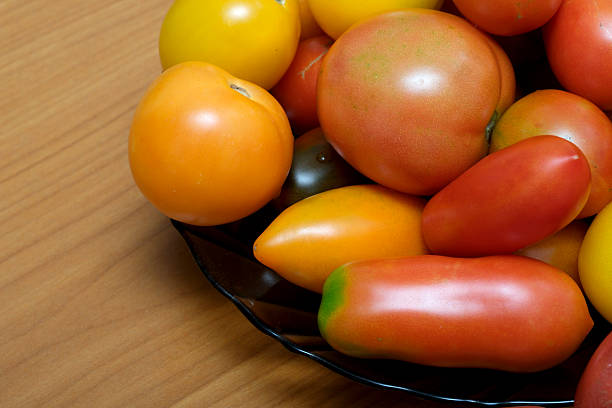 Colorful assortment of tomatoes brightens a wooden table, showcasing summer's bounty.