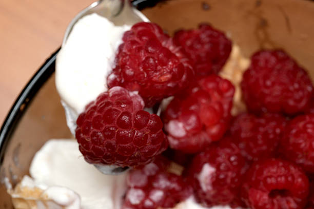 A spoonful of fresh raspberries atop smooth cream, perfect for summer enjoyment.