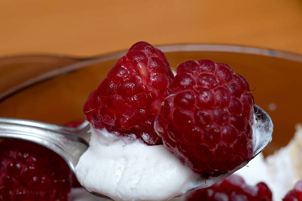 A spoonful of fresh raspberries rests on smooth, creamy delight, tempting taste buds.