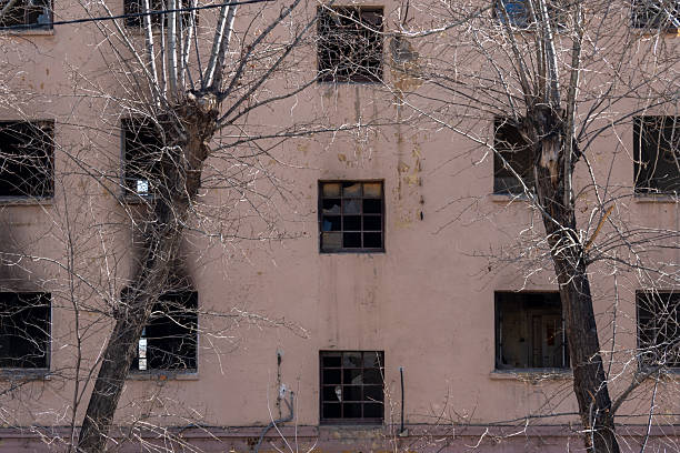 istock Abandoned building with empty windows and bare trees creating a haunting atmosphere in a desolate urban environment showcasing decay and neglect concept 2235721864