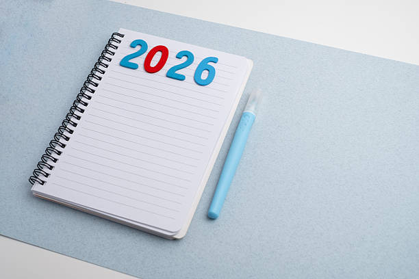 istock Happy New Year 2026 and a notepad on a colored background. Layout for writing annual business plans, schedules, as well as New Year's resolutions and goals. 2235722757