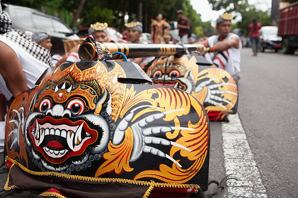 Denpasar, Bali island, Indonesia - June 23, 2018: Young men dressed in ethnic Balinese costumes with Barong, Bona masks before ritual temple procession at street of Denpasar