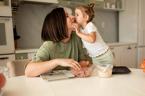 istock Cute Child Kissing Mom in Kitchen During Meal Preparation 2235725132