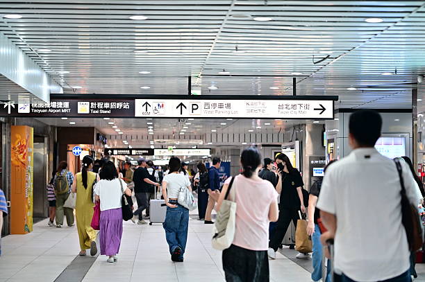 Taiwan - Jul 21, 2025: Busy pedestrian corridor in Taipei Main Station showing travelers with luggage navigating directional signs to Taoyuan Airport MRT, taxi stand, and underground shopping street.