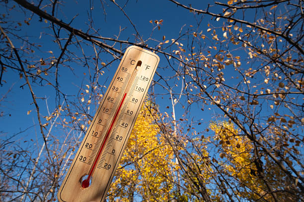 istock Thermometer against background an autumn forest and blue sky on hot day. 2235729716