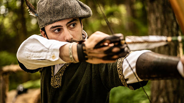 istock Archer in Medieval Attire Aiming Longbow in Forest 2235739404