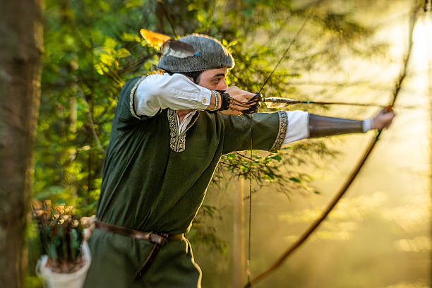 istock Archer in Medieval Attire Aiming Longbow in Sunlit Forest 2235739408
